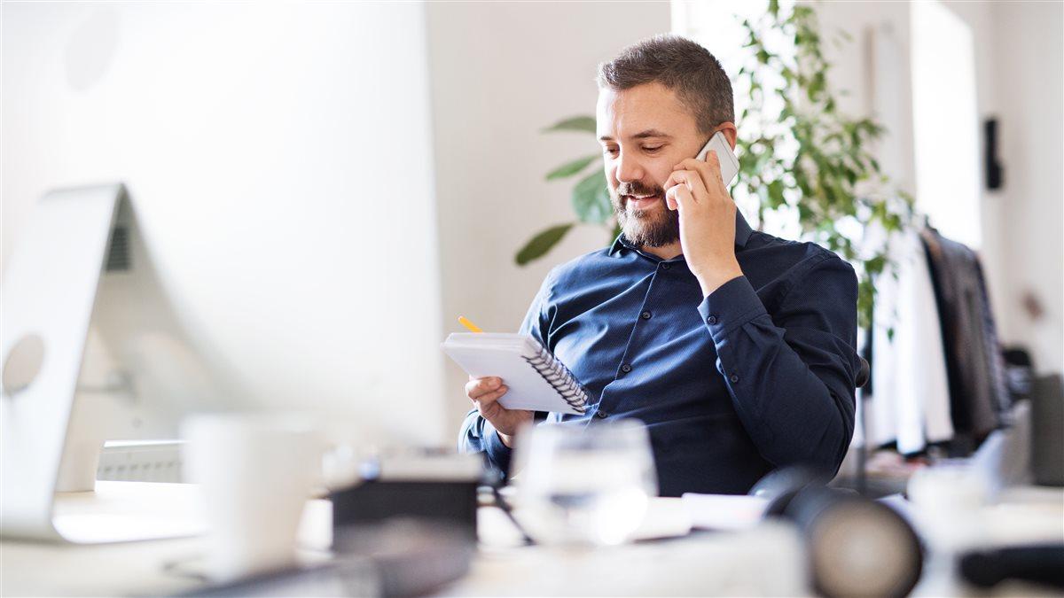 Businessman in wheelchair with smartphone at the desk in the office, making a phone call.